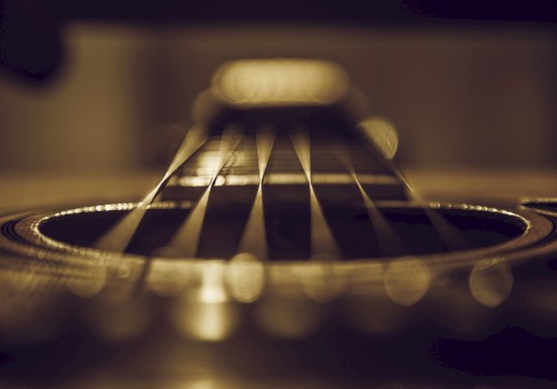 Close-up view of an acoustic guitar's strings and soundhole, captured with a shallow depth of field for a dramatic effect.