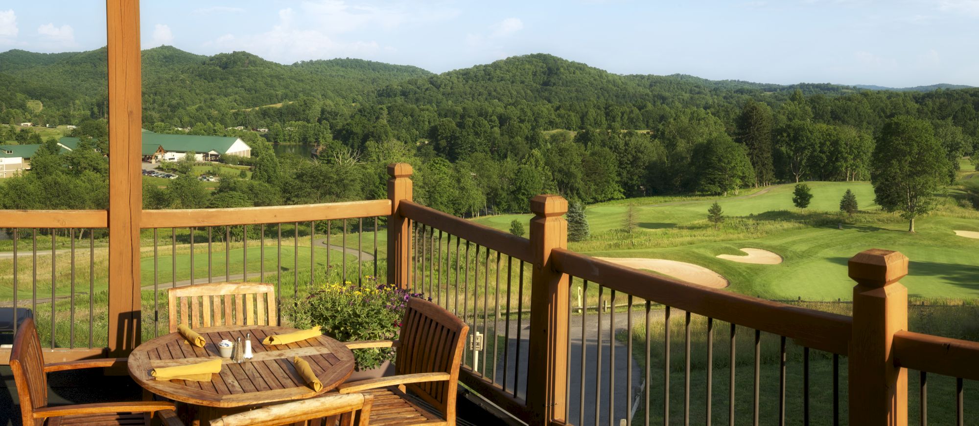 Wooden patio overlooking a golf course and a landscape of rolling green hills under a clear sky, ending the sentence.