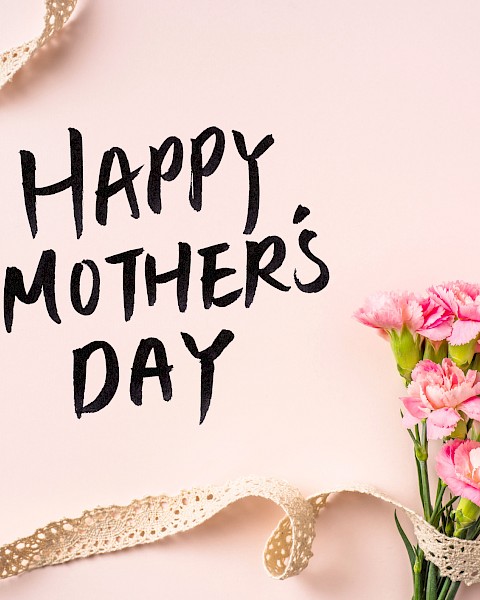 Happy Mother’s Day card on a soft pink background with a bouquet of pink flowers and a gold ribbon curling around it.