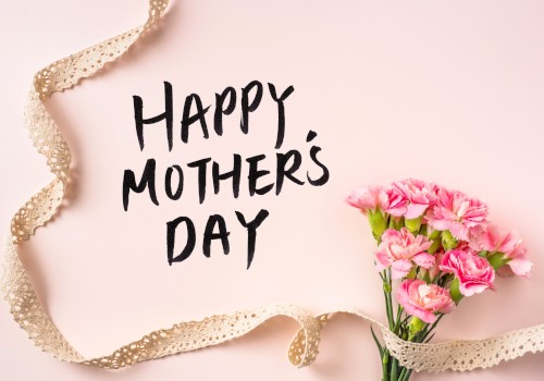 Happy Mother’s Day card on a soft pink background with a bouquet of pink flowers and a gold ribbon curling around it.