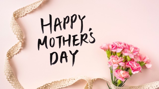 Happy Mother’s Day card on a soft pink background with a bouquet of pink flowers and a gold ribbon curling around it.