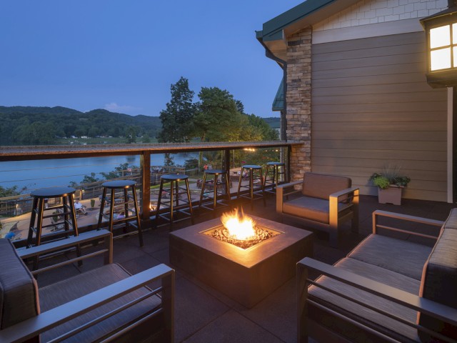 A cozy outdoor patio with seating, a fire pit, and a lake view at dusk, creating a relaxing atmosphere for evening gatherings.