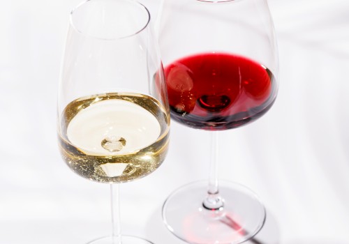 Two wine glasses, one with white wine and the other with red wine, on a white surface with shadows.