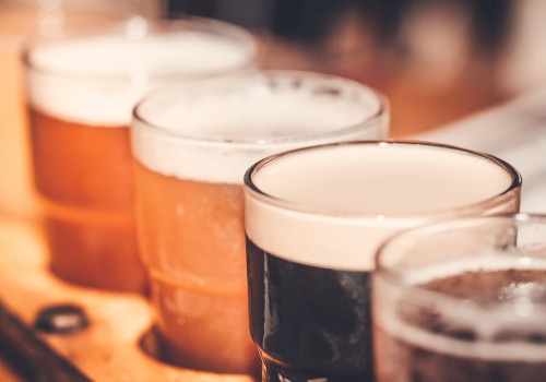 Several pints of beer are lined up on a wooden surface, with some beers darker and some lighter in color.
