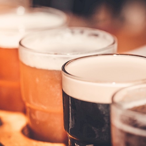 Several pints of beer are lined up on a wooden surface, with some beers darker and some lighter in color.