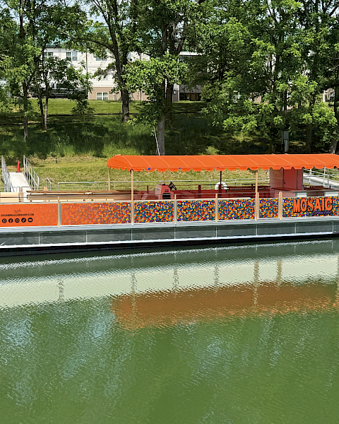 A colorful floating boat with orange canopy named 