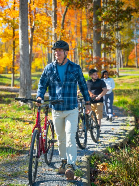People enjoy a fall bike ride through a scenic park with colorful autumn foliage on a sunny day.