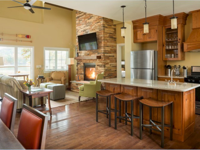 A cozy open-concept kitchen and living room with a fireplace, wooden accents, and a bright, inviting atmosphere.
