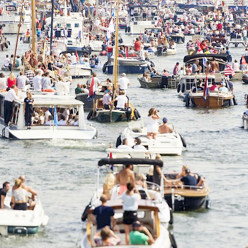 A crowded marina with numerous boats and many people enjoying a lively day on the water.