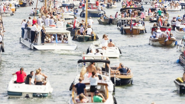 A crowded marina with numerous boats and many people enjoying a lively day on the water.