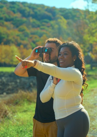 Photo of couple looking through binoculars with forest in background