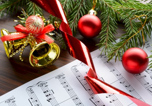 Christmas decorations with ornaments, a tree branch, a bell, ribbon, and sheet music for holiday celebrations.