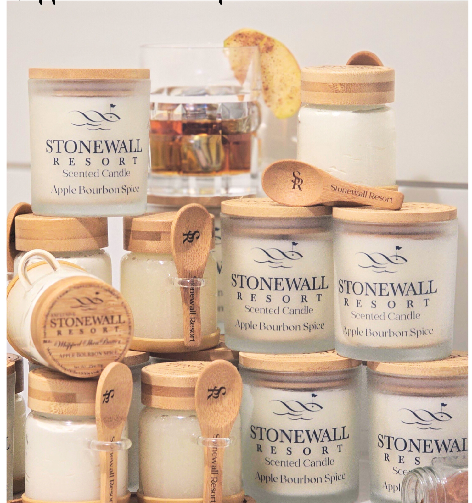 Assorted apple- and bourbon-scented candles and wax melts from Stonewall Resort, with wooden lids and spoons for easy use, on a display.