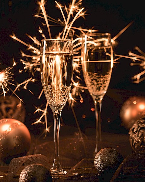 Two champagne glasses, sparklers, and decorative ornaments create a festive atmosphere.