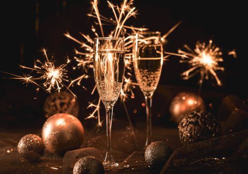 Two champagne glasses, sparklers, and decorative ornaments create a festive atmosphere.