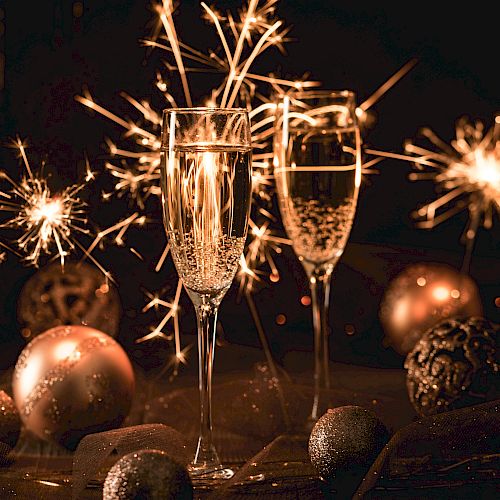 Two champagne glasses, sparklers, and decorative ornaments create a festive atmosphere.