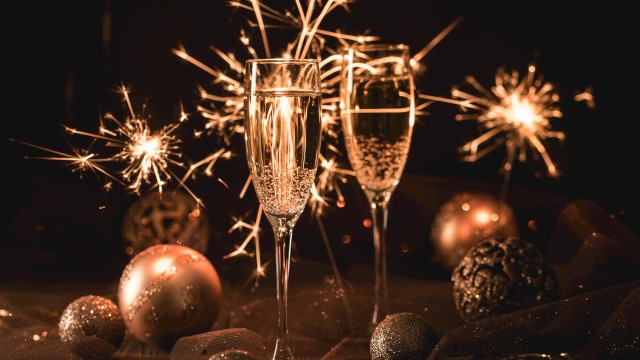 Two champagne glasses, sparklers, and decorative ornaments create a festive atmosphere.
