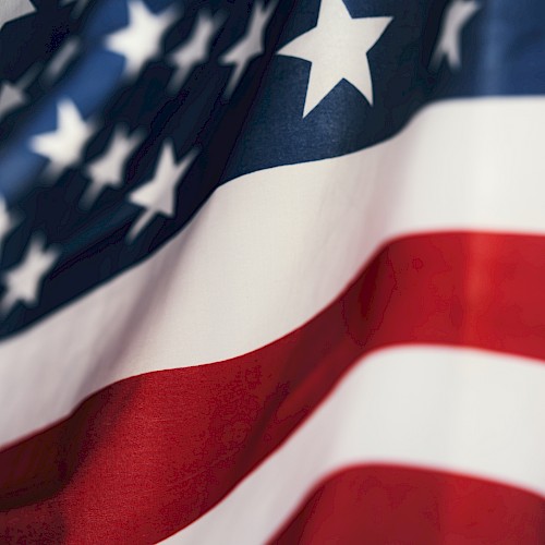 The image shows a close-up of the American flag, featuring stars and stripes in red, white, and blue.