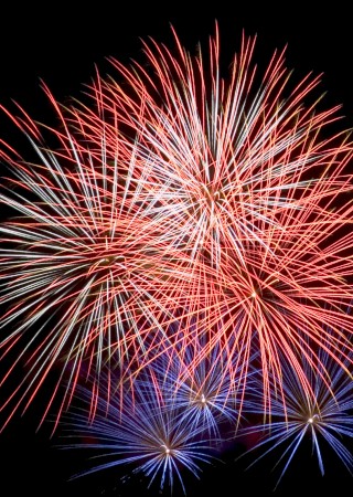 The image shows a vibrant fireworks display with red, white, and blue bursts against a dark sky.