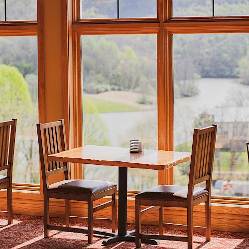 A table and two chairs against picturesque floor to ceiling windows. The table is open for guests to sit and dine.