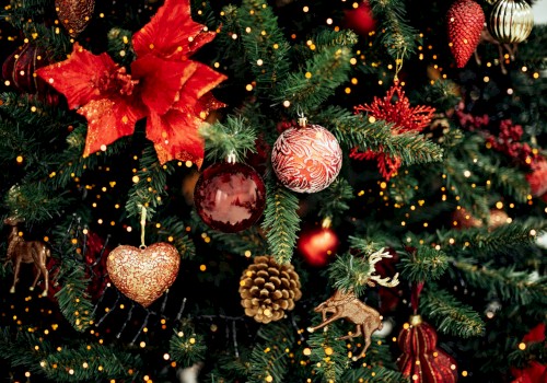 The image shows a decorated Christmas tree with red ornaments, bows, pine cones, and golden lights, creating a festive atmosphere.