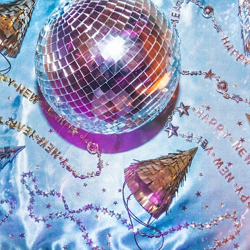 The image shows a disco ball, party hats, and 