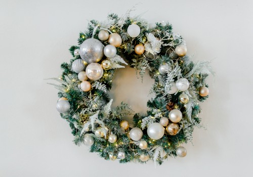 This is an image of a holiday wreath decorated with silver and gold ornaments, pine cones, and frosted greenery against a plain background.