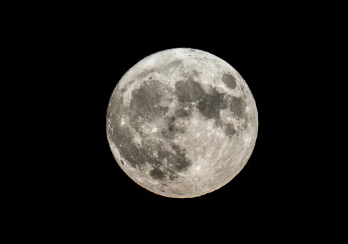 The image shows a clear, detailed view of the full moon set against a dark background. The surface features and craters are visible.