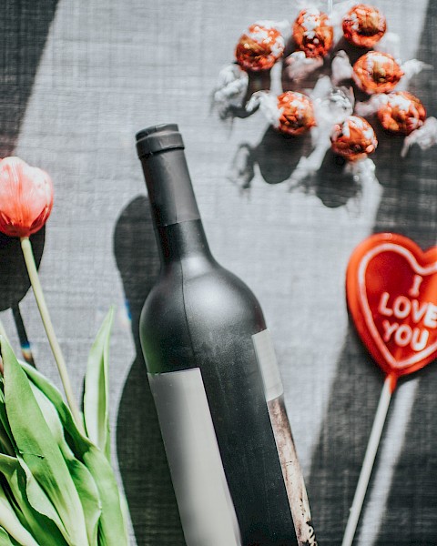 A bottle of wine, tulips, chocolate truffles, and a heart with 