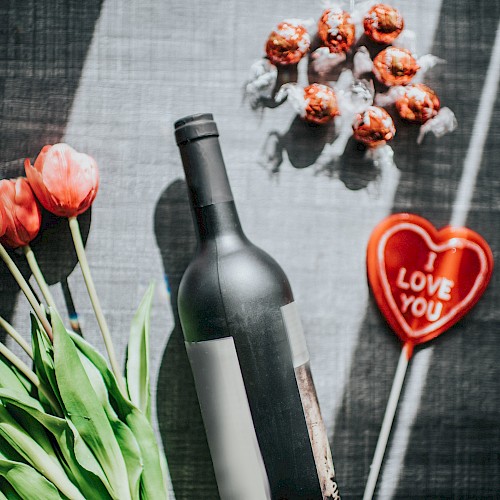 A bottle of wine, tulips, chocolate truffles, and a heart with 