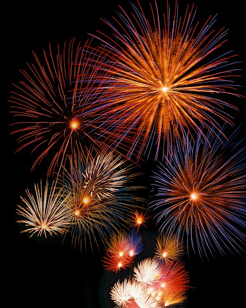 The image displays colorful fireworks exploding against a dark sky, creating a vibrant and festive display with bursts of light and color.