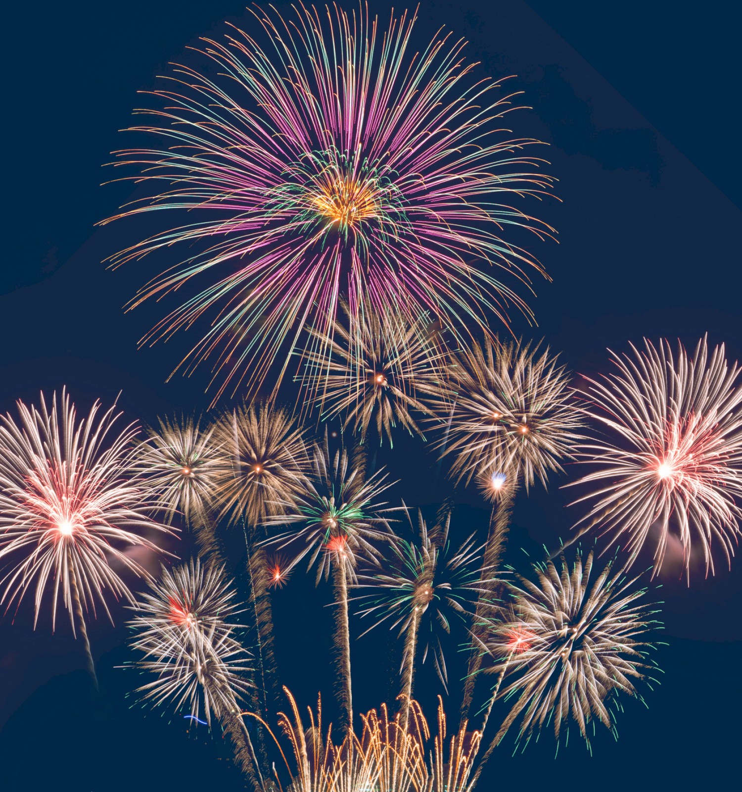 The image shows a vibrant display of fireworks exploding in the night sky, creating colorful patterns with varied shapes and sizes.