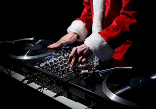 A person dressed in a Santa suit is DJing, using a mixer and turntables.