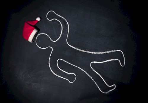 A chalk outline of a person on a dark surface with a Santa hat placed near the head of the outline, suggesting a playful holiday theme.