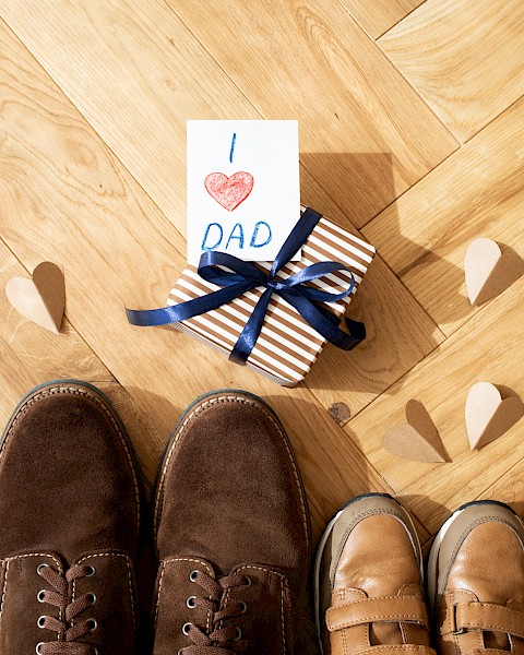 A pair of adult and child shoes, a gift wrapped in stripes with 