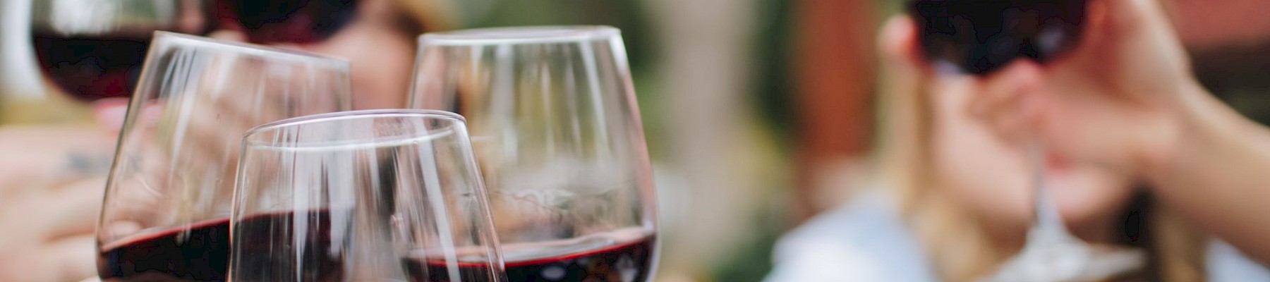 People raising glasses of red wine together in a celebratory toast.